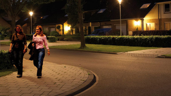 Två kvinnor promenerar på en gata belyst med vitt ljus från Philips