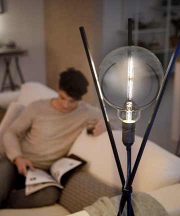En man läser bredvid en Philips modern designat LED-glödlampa