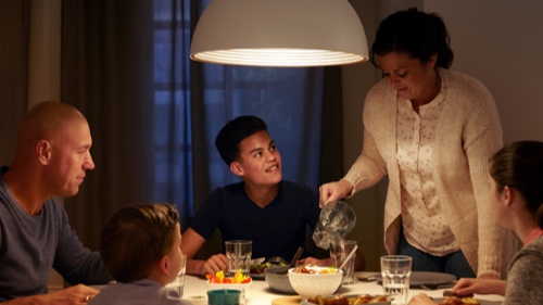 Familj som äter middag hemma under ett väl upplyst matbord