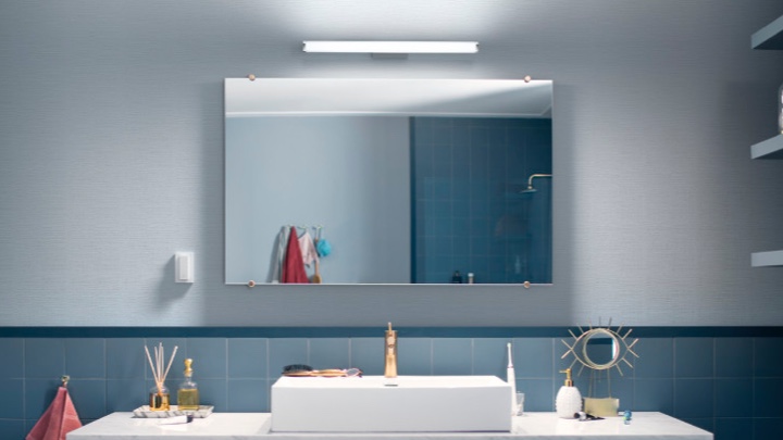 Vägglampa ovanför en spegel i badrummet