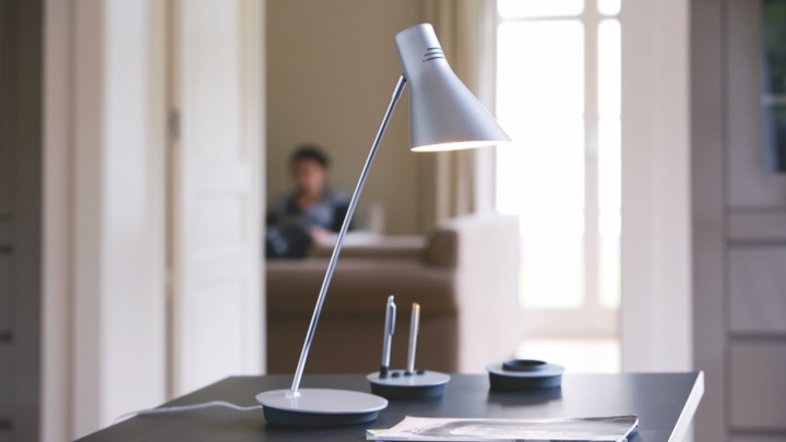 En bordslampa på ett skrivbord riktad mot papper och penna