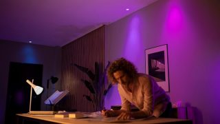 Philips Hue smarta LED-lampor skapar en livfull lila och rosa atmosfär i vardagsrummet och visar anpassningsbar stämningsbelysning för filmkvällar och avkoppling i moderna hem.