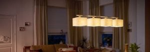 Modern LED-pendellampa med flera tygskärmar lyser upp ett mysigt vardagsrum och visar energieffektiva och elegant belysninglösningar för en mysig kvällskomfort.